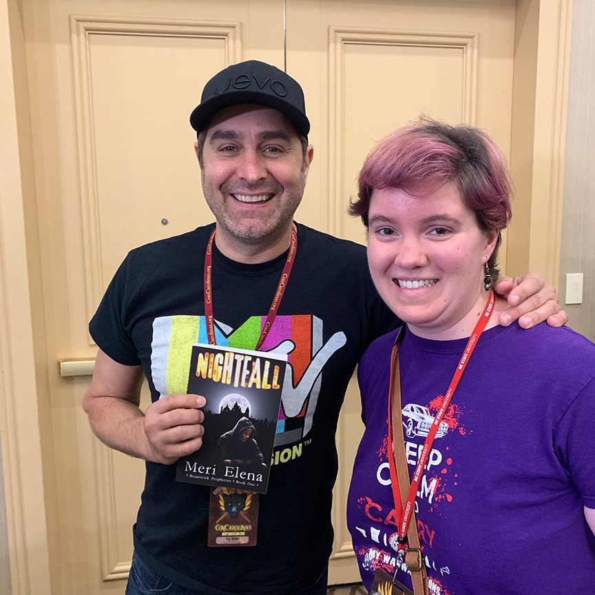 Tory Belleci posing with pink-haired woman and book
